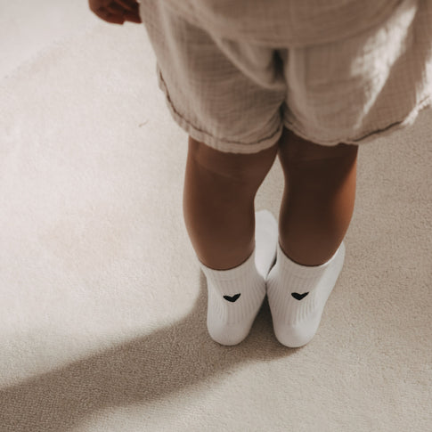 Kind trägt weiße Socken mit schwarzem Herz von Eulenschnitt