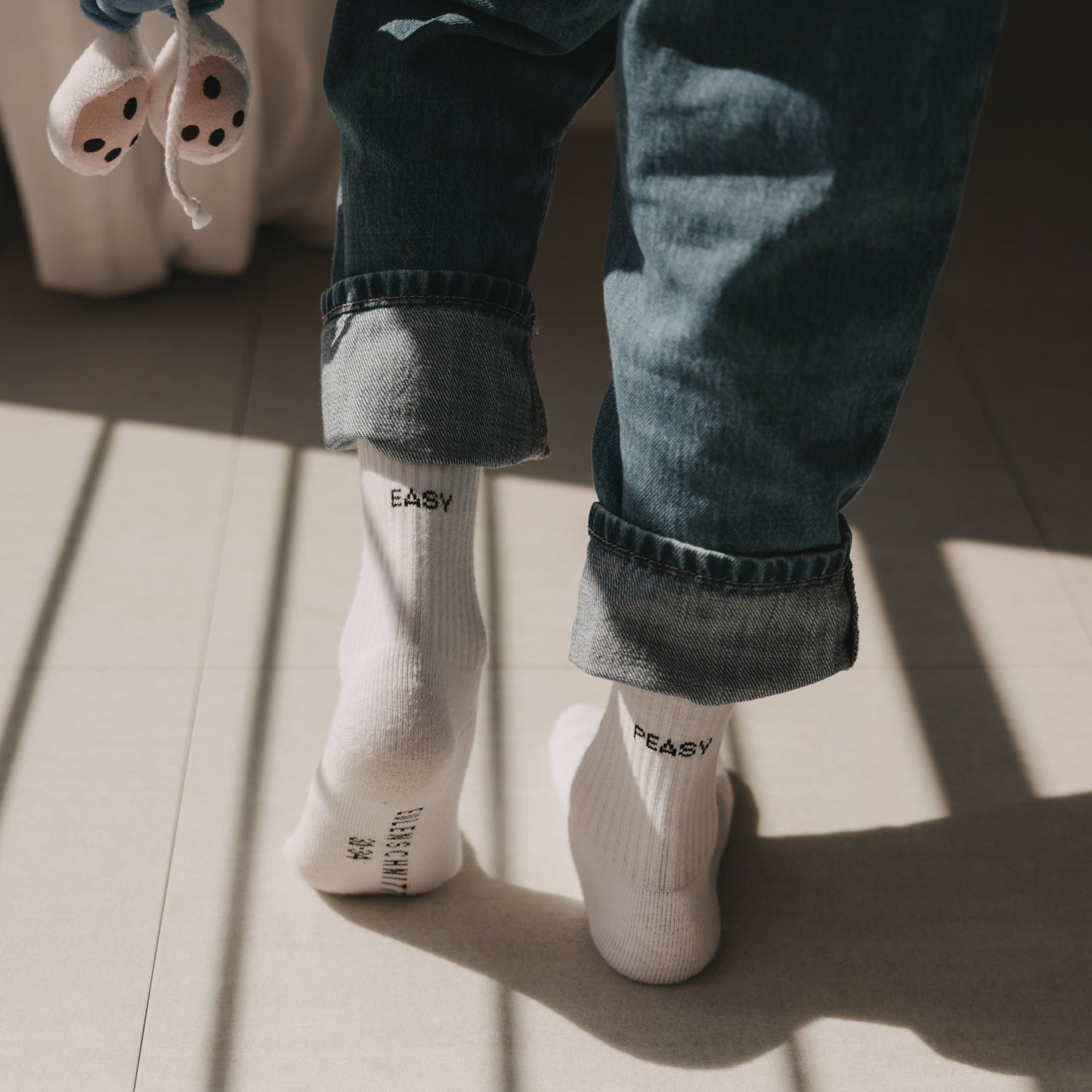 Kind trägt weiße Easy Peasy Socken zu hochgekrempelter Jeans im warmen Sonnenlicht.