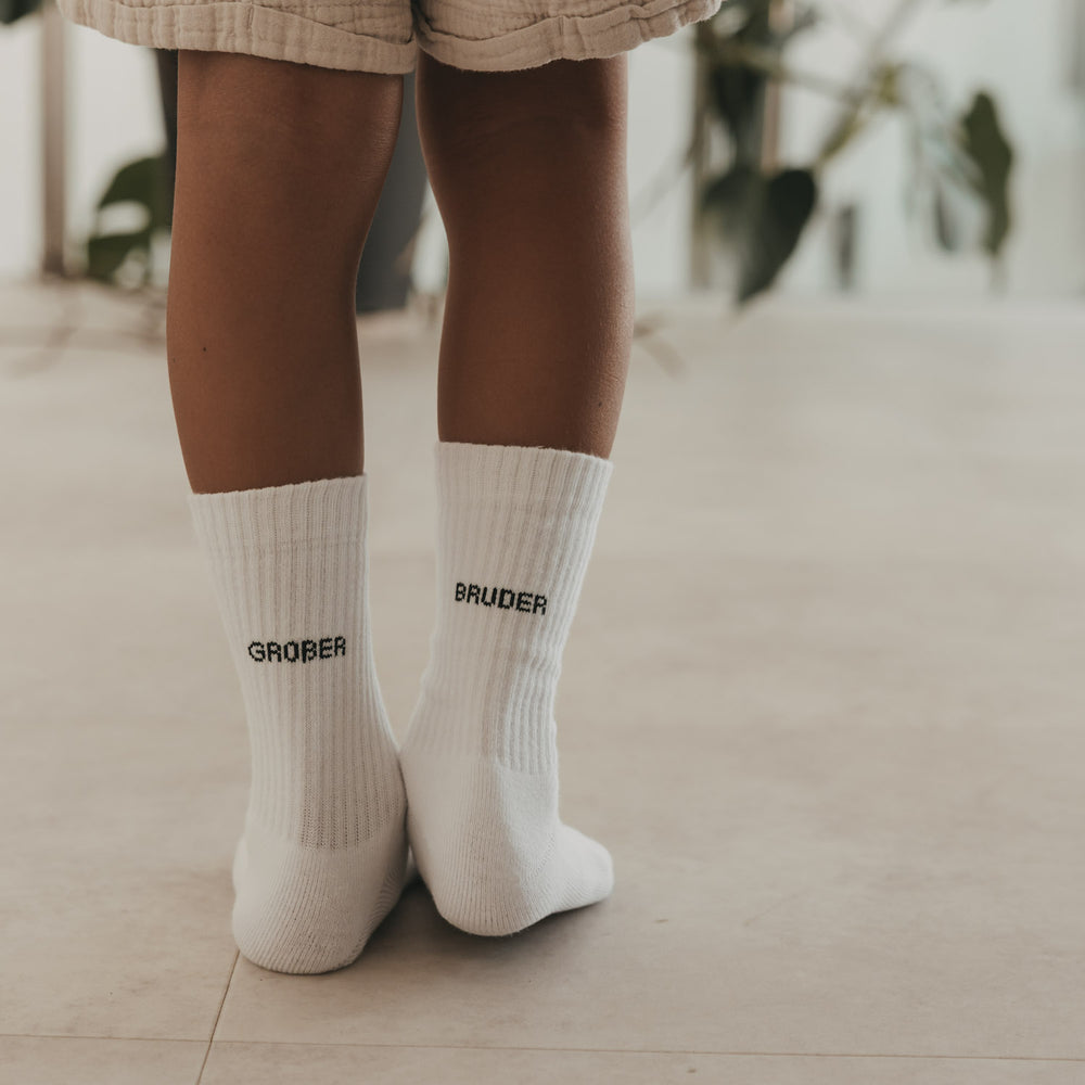 Weiße Kids Socken Großer Bruder mit schwarzem Schriftzug an Kinderfüßen