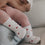 Babybeine mit weißen Herzsocken in Händen gehalten, liebevolle Szene mit weichen Textilien