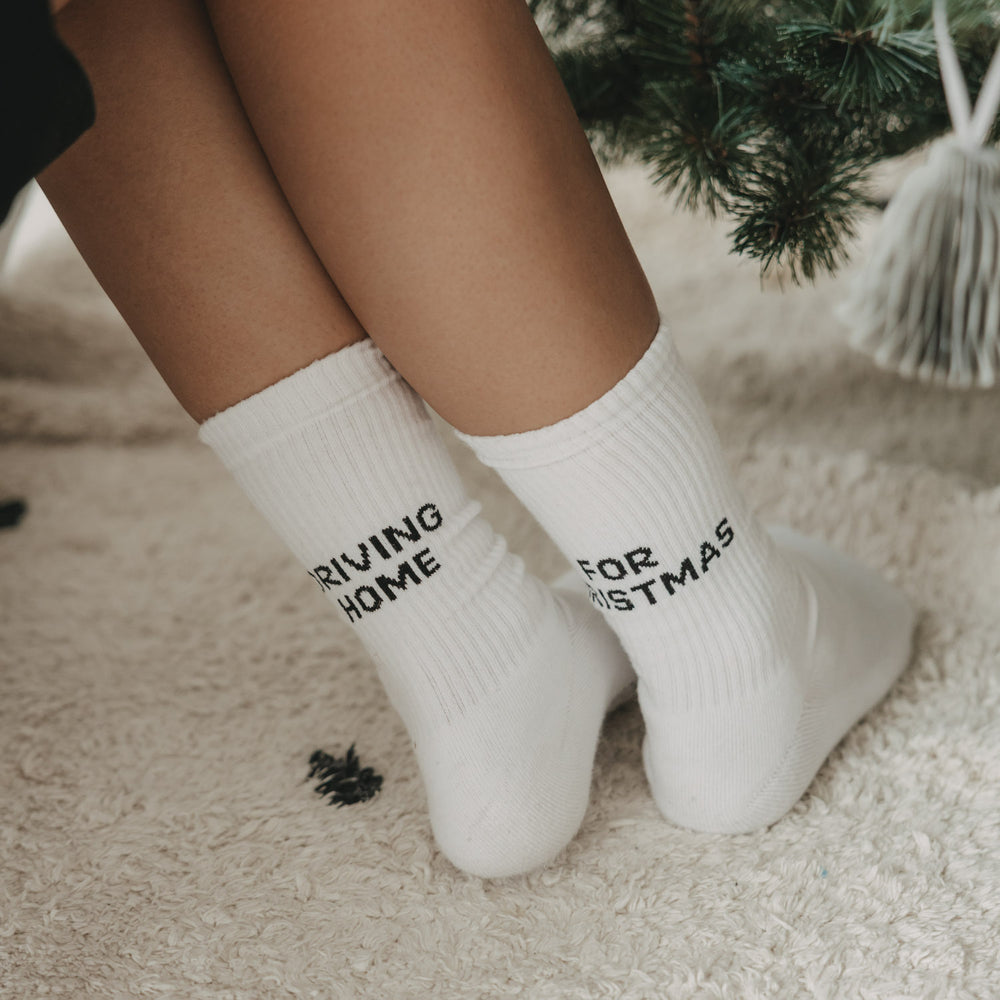 Socken Driving Home for Christmas getragen vor einem Weihnachtsbaum
