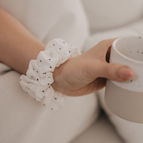 Weißes Scrunchie mit schwarzen Herzen am Handgelenk getragen