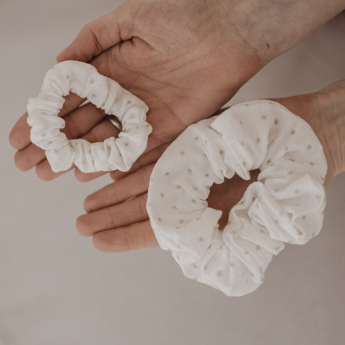 Zwei Scrunchies mit Blumenmuster in unterschiedlichen Größen in den Händen präsentiert