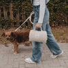 Person trägt cremefarbene Hundedecke mit Griff beim Spaziergang mit Hund