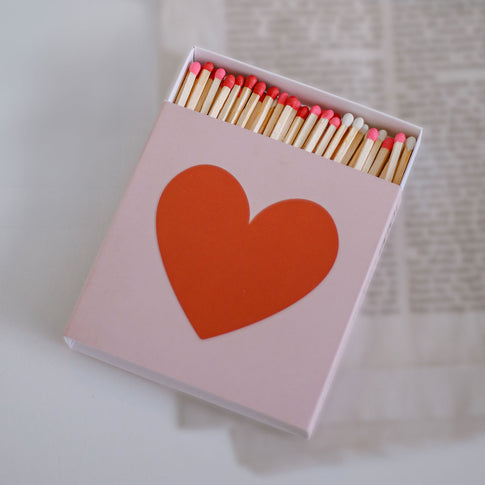 Offene Streichholzschachtel mit Herzdesign und farbigen Zündköpfen in Nahaufnahme.