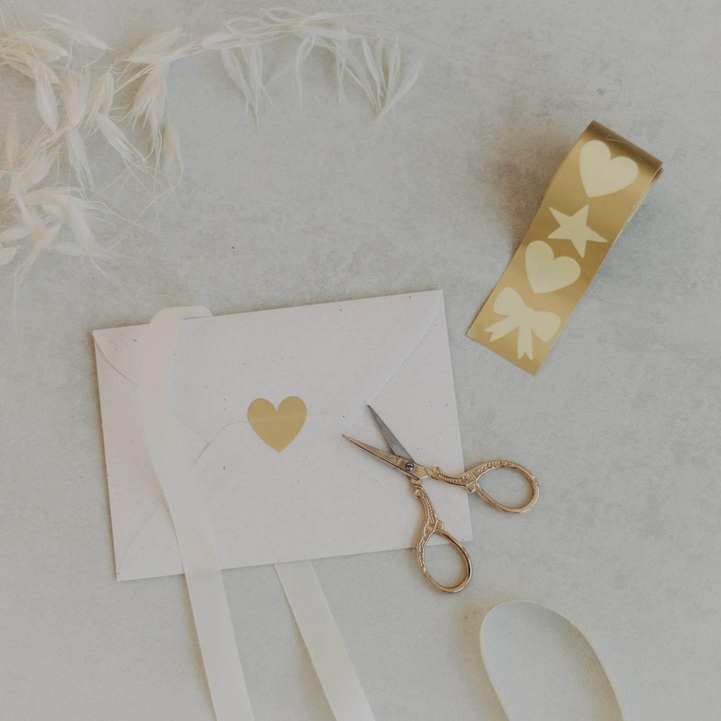 Stickerrolle mit goldenen Motiven Herz, Stern, Schleife und Schere auf hellem Untergrund