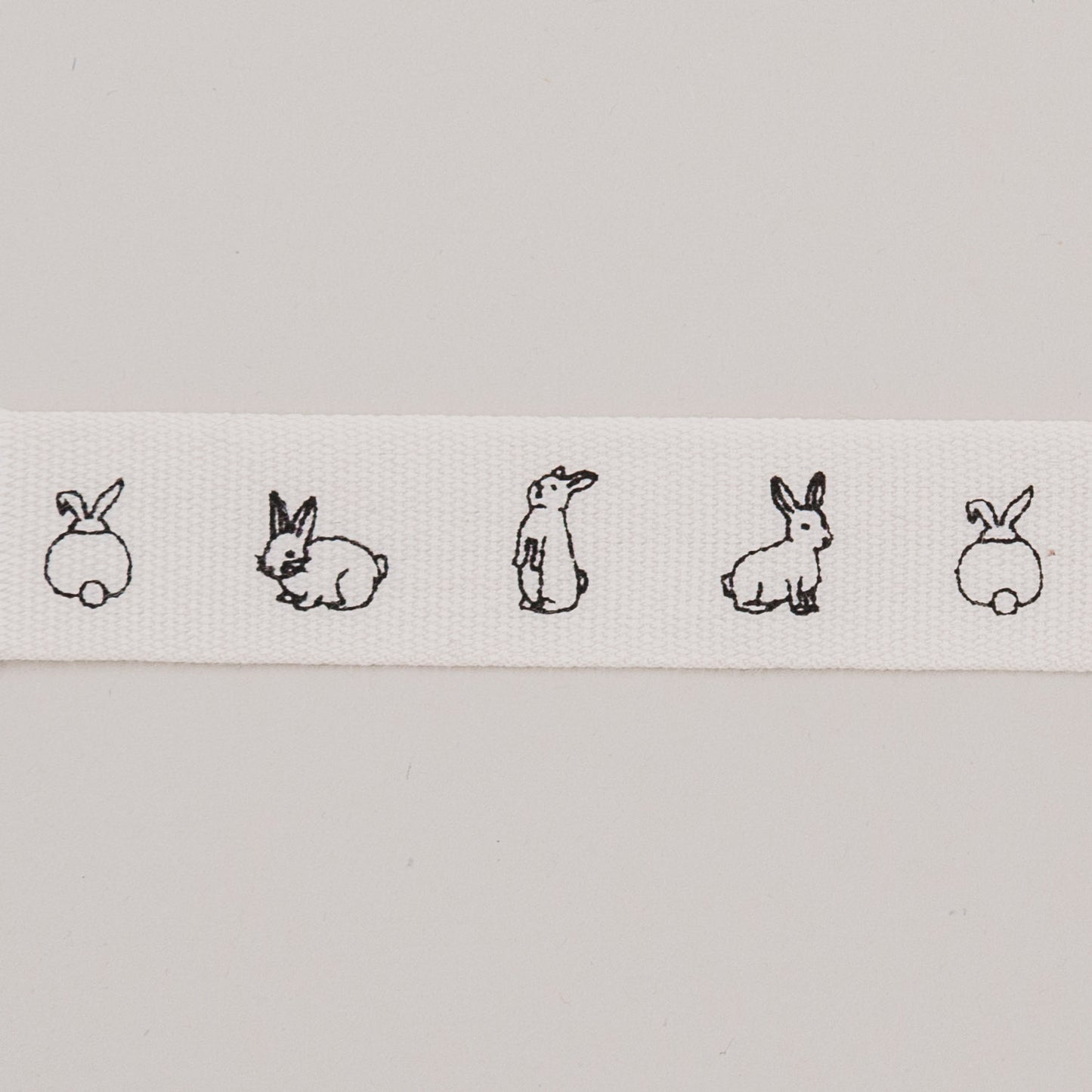 Nahaufnahme des weißen Geschenkbandes mit feinen schwarzen Kaninchenzeichnungen.