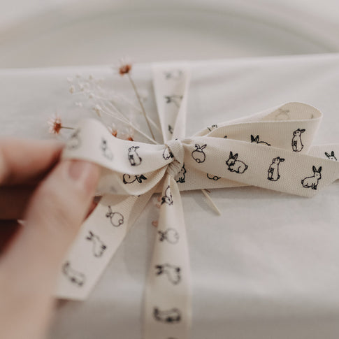Nahaufnahme einer Schleife aus Kaninchen-Geschenkband mit feinen Trockenblumen.