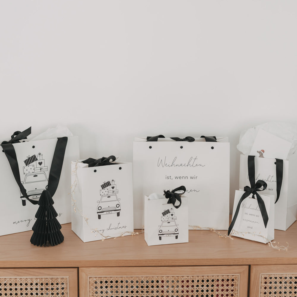 Geschenktüten Weihnachten dekoriert mit schwarzer Schleife und Tannendeko
