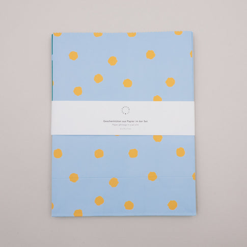 Flach liegende Papier-Geschenktüten mit Punkten im Set, gebündelt mit Banderole
