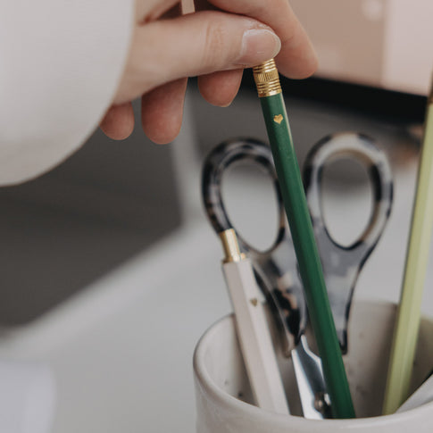 Grüner Bleistift mit Herzdetail in Becher mit Schere und weiteren Stiften