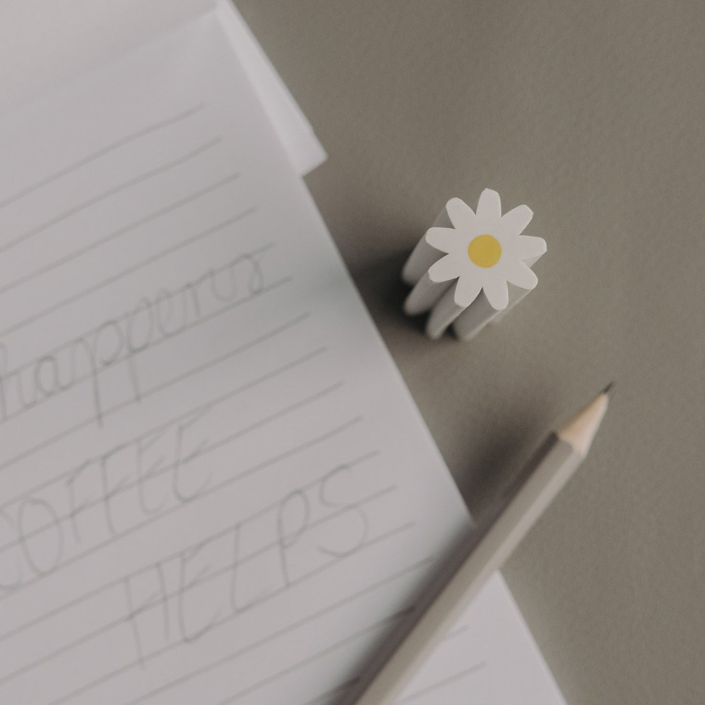 Radiergummi Daisy neben Notizblock und Bleistift auf Schreibtisch