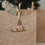 Weihnachtliche Kraftpapier-Geschenktüte mit weißen Wintermotiven und dekorativem Schlitten-Anhänger