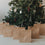 Weihnachtliche Kraftpapier-Geschenktüten mit verschiedenen weißen Motiven vor beleuchtetem Tannenbaum