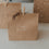 Braune Geschenktüte aus Kraftpapier mit weißem Schriftzug „Frohe Weihnachten“ und Holzklammer