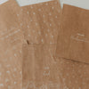Verschiedene Geschenktüten aus Kraftpapier mit weißen Weihnachtsmotiven und Schriftzügen
