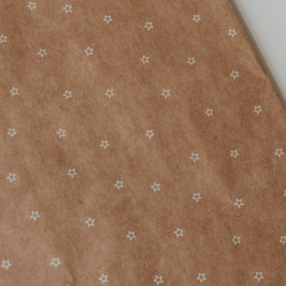 Detailansicht von Kraftpapier-Geschenktüte mit kleinem weißen Sternenmuster