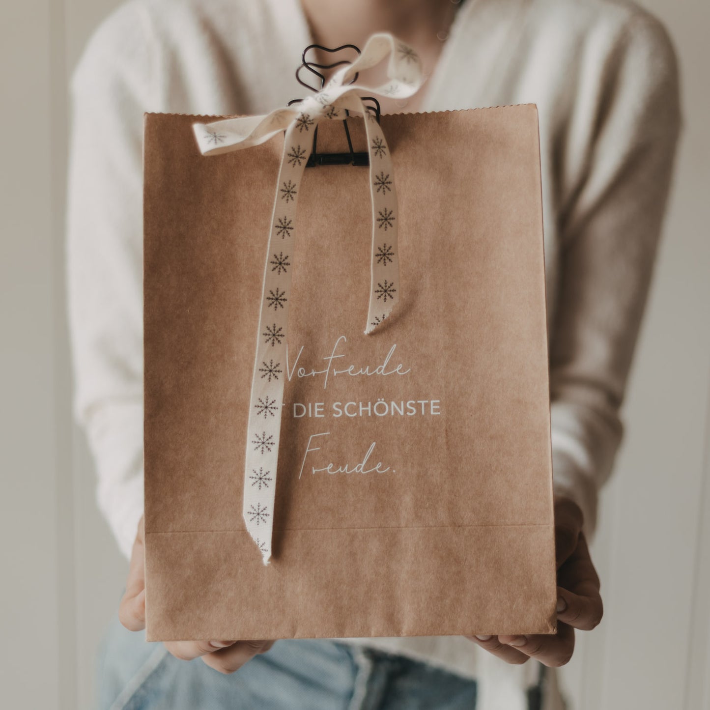 Geschenktüte aus Kraftpapier mit „Vorfreude ist die schönste Freude“ und Schneeflocken-Schleife