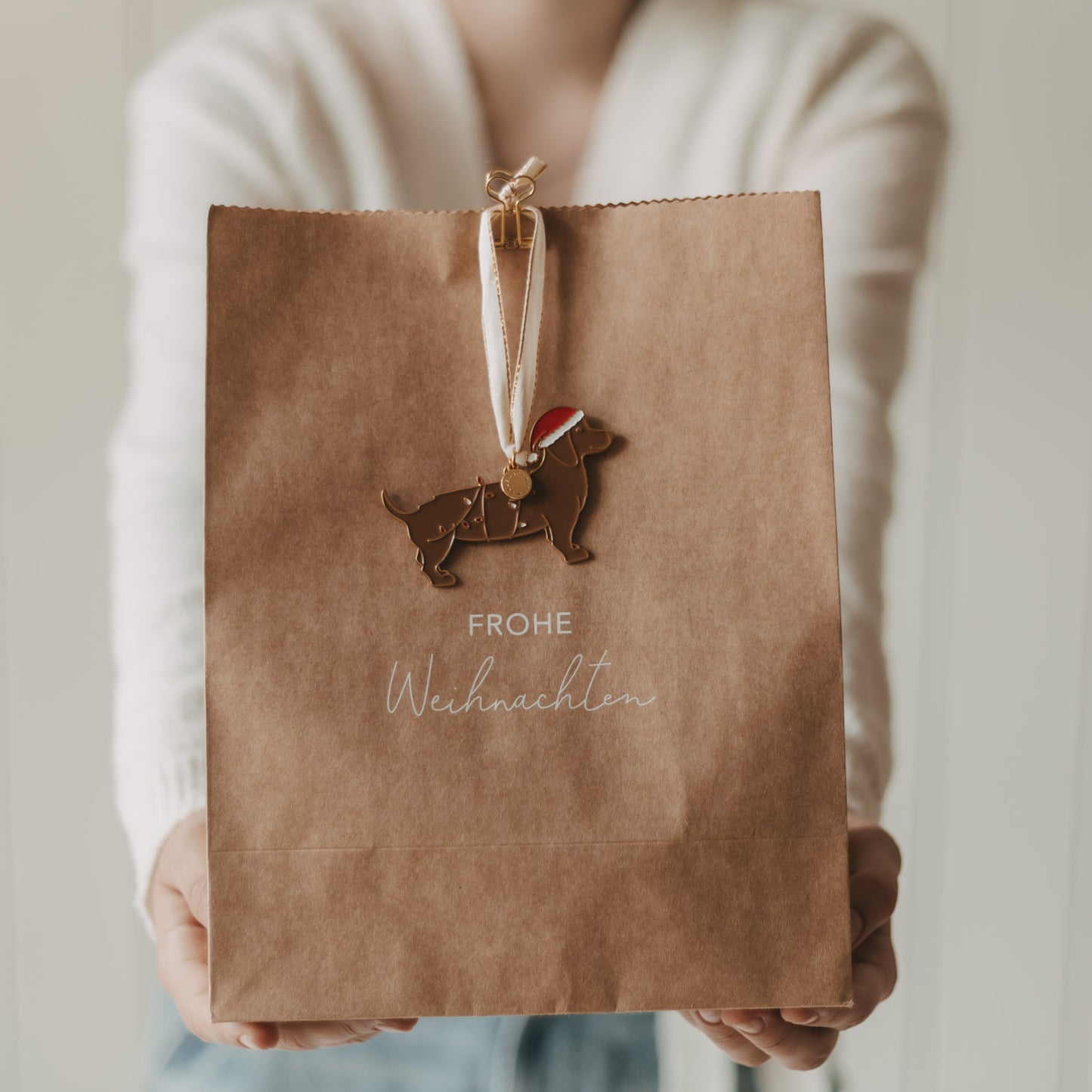 Geschenktüte aus Kraftpapier mit „Frohe Weihnachten“ und weihnachtlichem Hundeanhänger