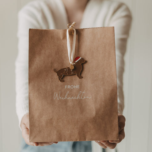 Geschenktüte aus Kraftpapier mit „Frohe Weihnachten“ und weihnachtlichem Hundeanhänger