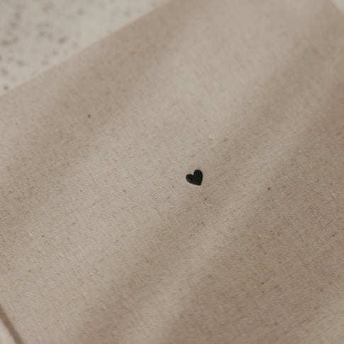 Detail des beigen Leineneinbands mit kleinem schwarzem Herz auf der Vorderseite des Gästebuchs