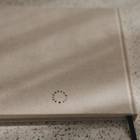 Rückseite des beigen Buchs mit Eulenschnitt Logo, Leineneinband und schwarzem Leseband