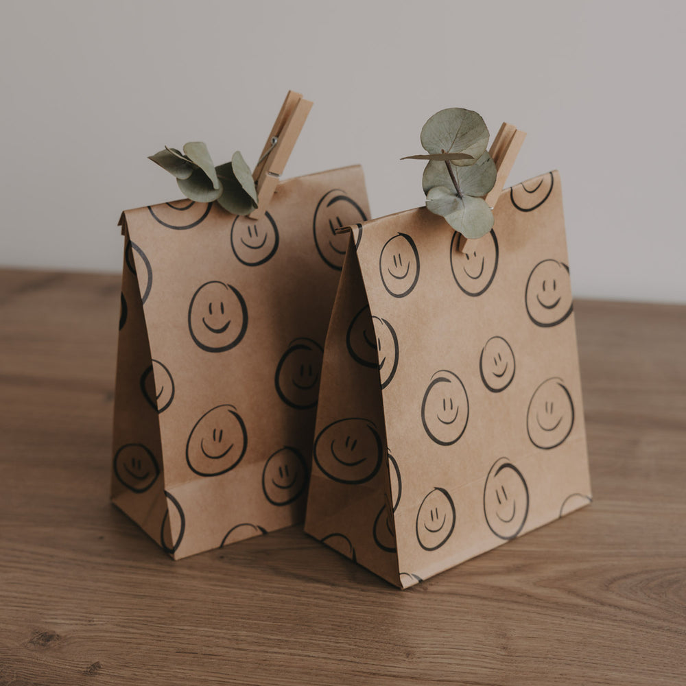 Papiergeschenktüten aus braunem Kraftpapier mit Smileys, modern und verspielt gestaltet