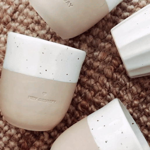 Becher mit der Prägung "Hello New Day" wird in verschiedenen Winkeln in die Kamera gehalten und gedreht. Dahinter liegen noch andere Becher.